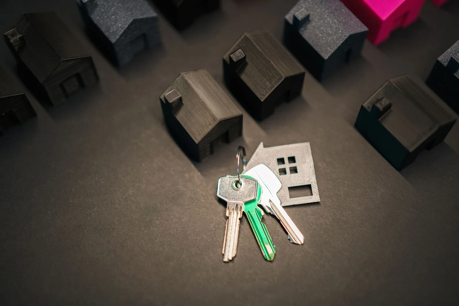 Miniature houses and keys arranged to represent a mortgage decision between keeping or replacing a loan
